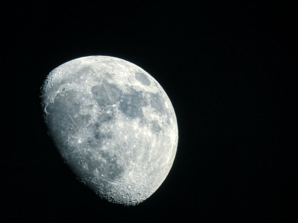 Close up view of a full moon that is emerging from the darkness.