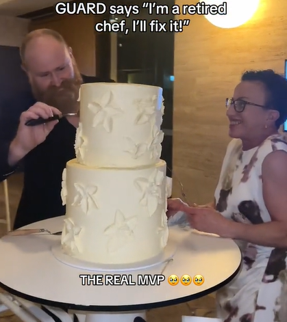 A security guard fixes a wedding cake with frosting.