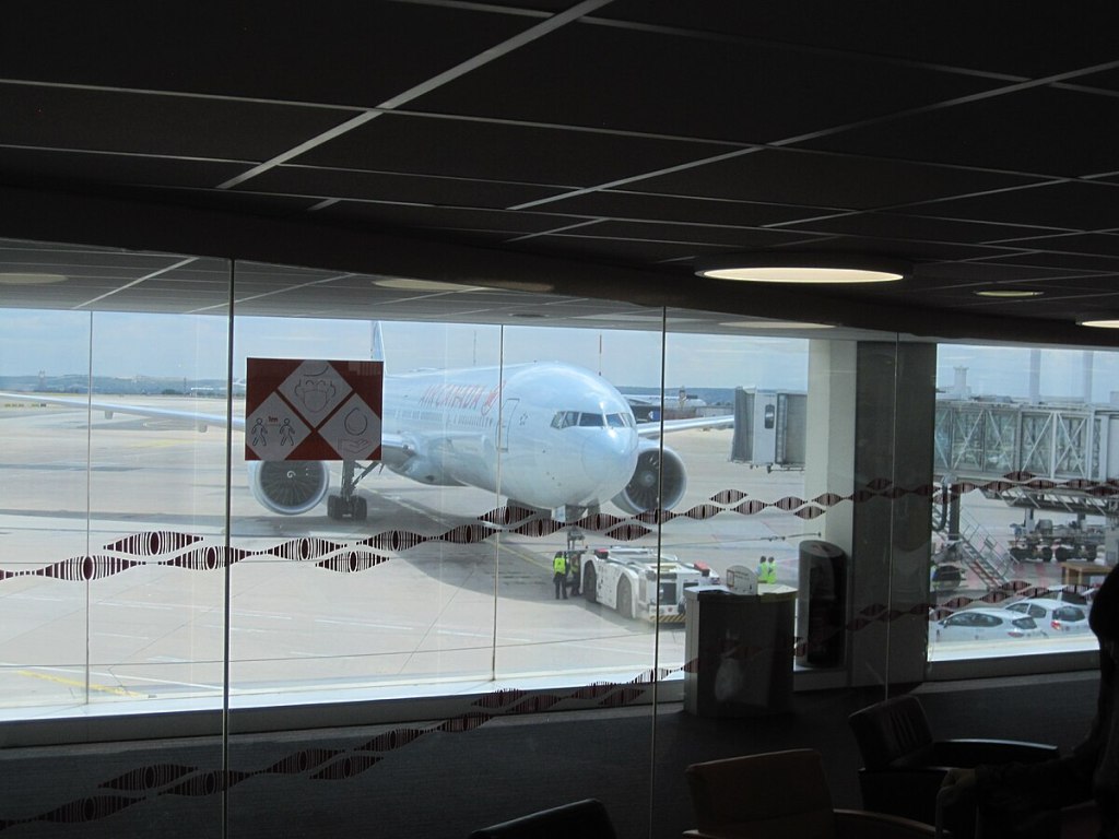 View from inside an airport. From this view, we see the outside where a plane is on the ground.