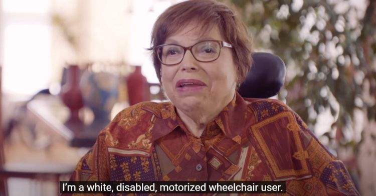 Image shows Judy Heumann, a disability rights activist. Wording along the bottom reads, "I'm a white, disabled, motorized wheelchair user."