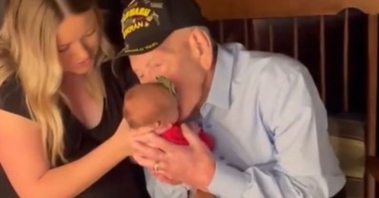 WWII Vet leans down to kiss the great-great-granddaughter he just met.