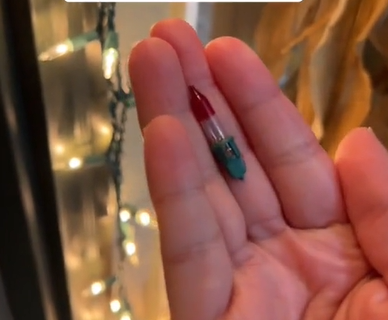 hand holding a red bulb from Christmas string lights