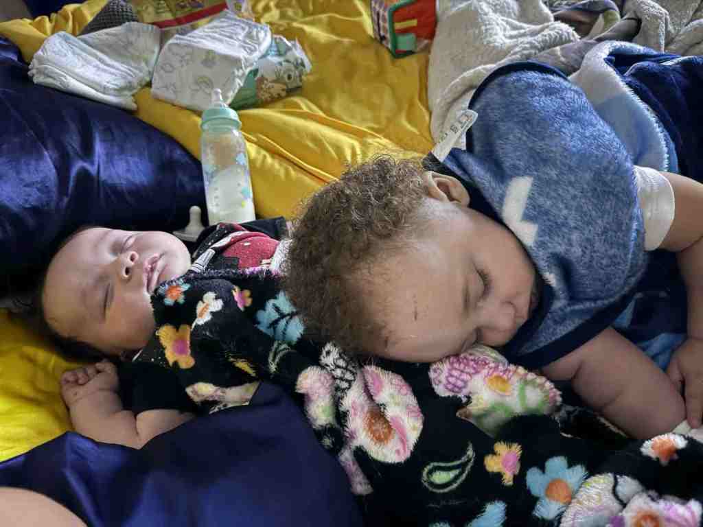 Baby Lord sleeps on his back as his older brother, Princeton, partially lays on him while he sleeps, too.