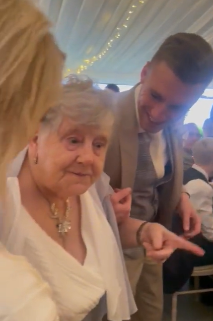 Grandmother points as she happily shares that her granddaughter is wearing her dress.