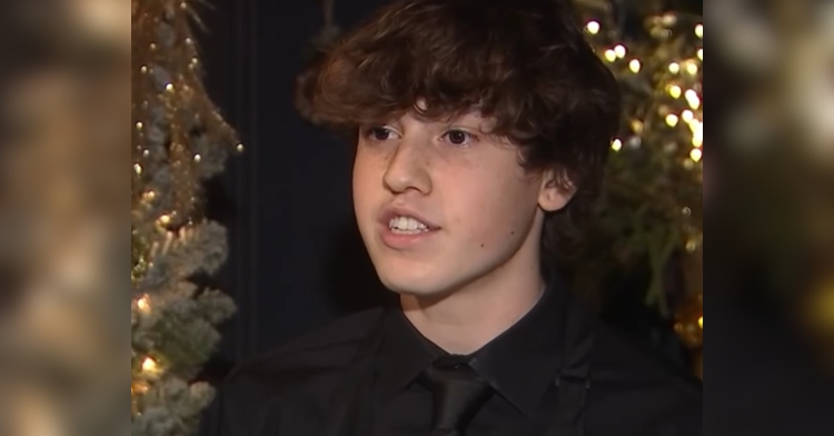 Teen busboy, Jackson Teran, talks to news crew near a tree lit with Christmas lights, recounting how he saved the life of a choking man.