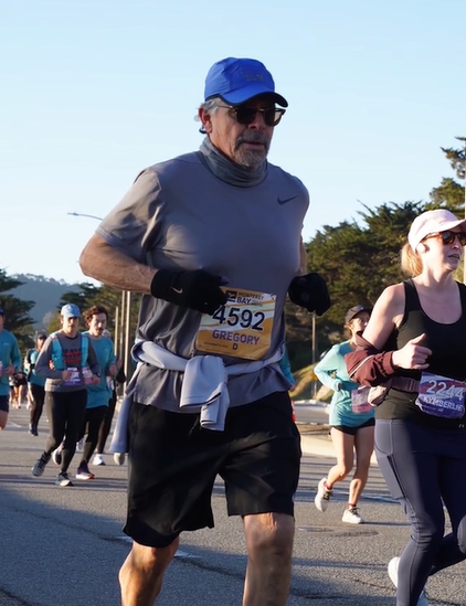 A man, with the name tag of Gregory D, runs with others in a half-marathon. 