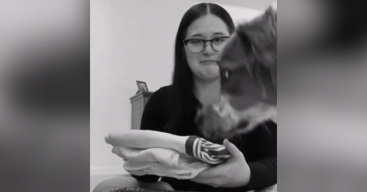 Mom looks over at her dog quizzically as she holds baby blankets.