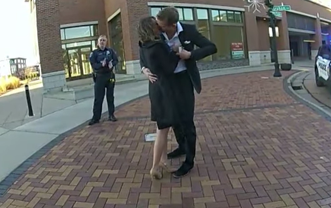 A man and a woman kiss after agreeing to get married in front of a police officer. 