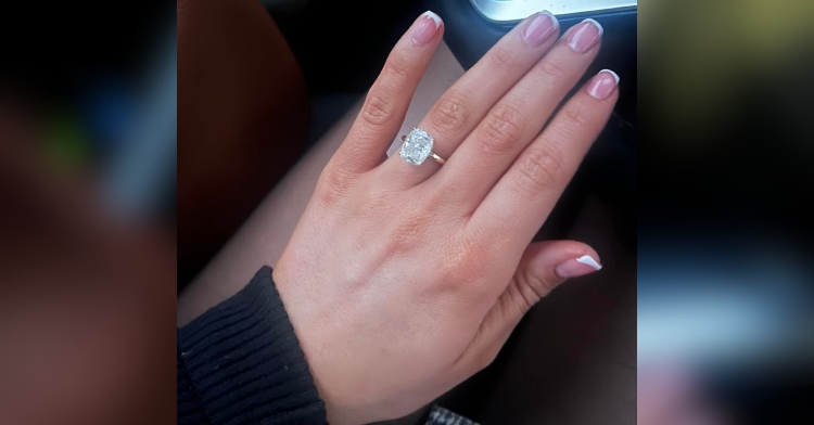 Bailey Davis holds out her hand to take a photo of her large engagement ring. She's sitting in a car.