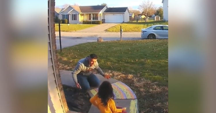 A dad and his little girl sit outside their home, using chalk to decorate the sidewalk. Dad looks at his daughter, shrugging.