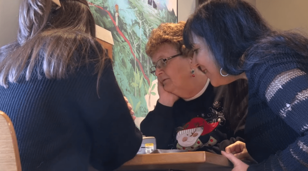 Jordyn, her mom Sharon, and Pat sit around a table and look at photos together.