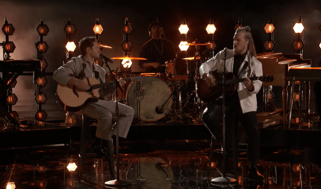 Niall Horan and Huntley sit on stools on "The Voice" stage, playing guitars as they sing a classic Bob Dylan song.