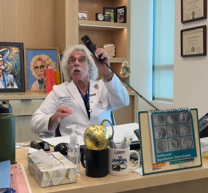 Dr. Larry Werlin sits at his desk. He talks as he holds out a phone.