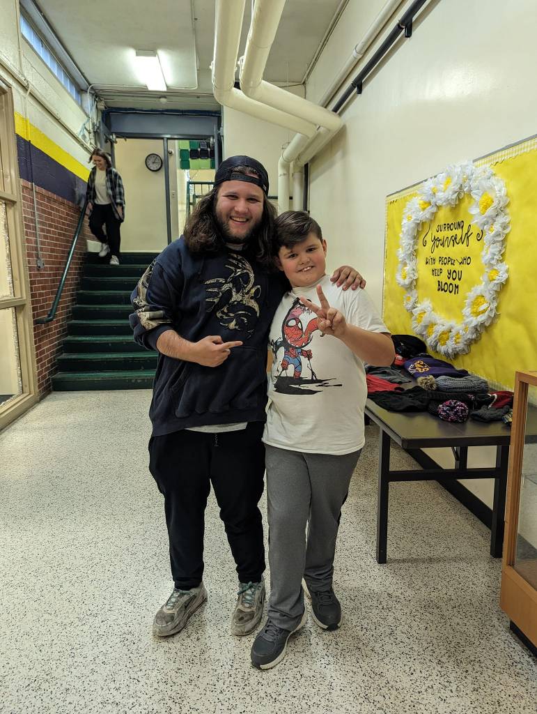 Janitor Ian Greenarch points and smiles at the boy he wrote a letter for, an arm around his shoulder. The boy, Daniel, smiles and gives a peace sign.