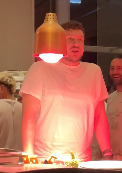 A man working at an Italian restaurant in the kitchen looks up as he sings.