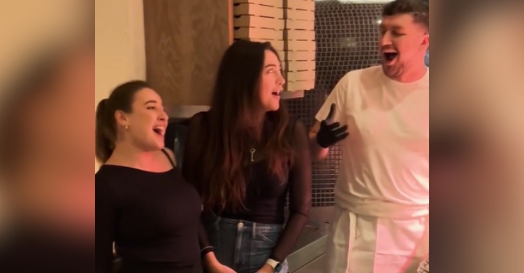 Three opera singers stand side by side, singing "Bella Ciao."