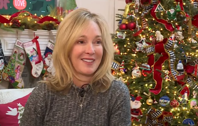 Woman in Kentucky smiles as she sits on her couch in the living room which is decorated for Christmas. Behind her is a Christmas tree, the one where the owl was found.