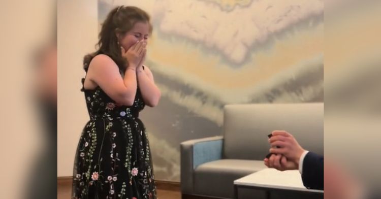 A young woman reacts to her boyfriend's proposal during a photo shoot.