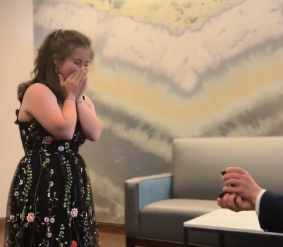 A young woman reacts to her boyfriend's proposal during a photo shoot. 