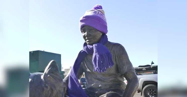 A statue wearing a purple hat and scarf for winter.