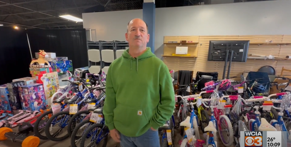 John Peeler stands in front of a large amount of kids' bikes and toys.
