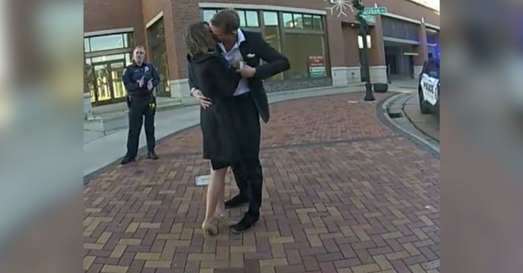 A man and a woman kiss after agreeing to get married in front of a police officer.
