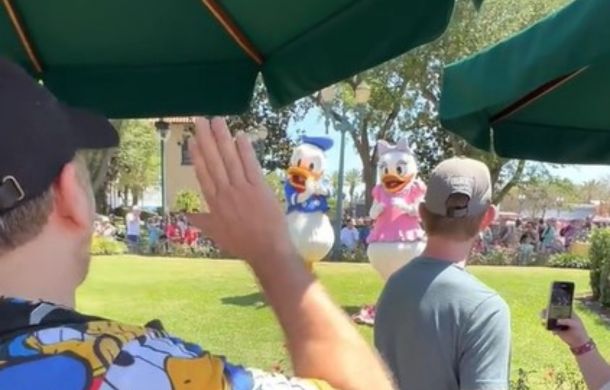 Daniel Ross (voice actor) waving to Donald Duck during a celebration of Donald's 90th birthday. Daniel is the guy wearing the shirt with images of Donald Duck all over it.