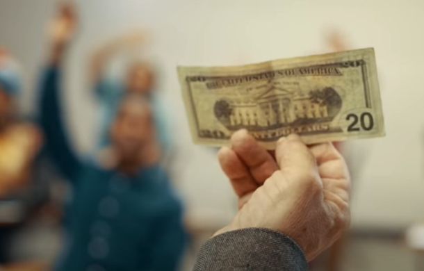 Professor holding up a 20-dollar bill he is using for a lesson.