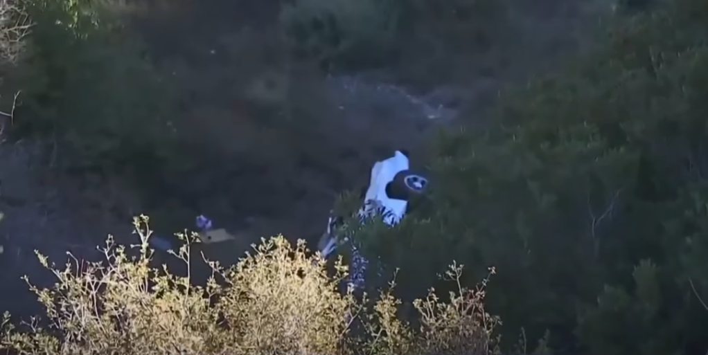 View of a California woman's white car at the bottom of a cliff in Angeles National Forest.