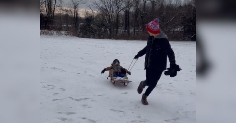 A teen boy pulls his disabled brother on an adaptive sled.