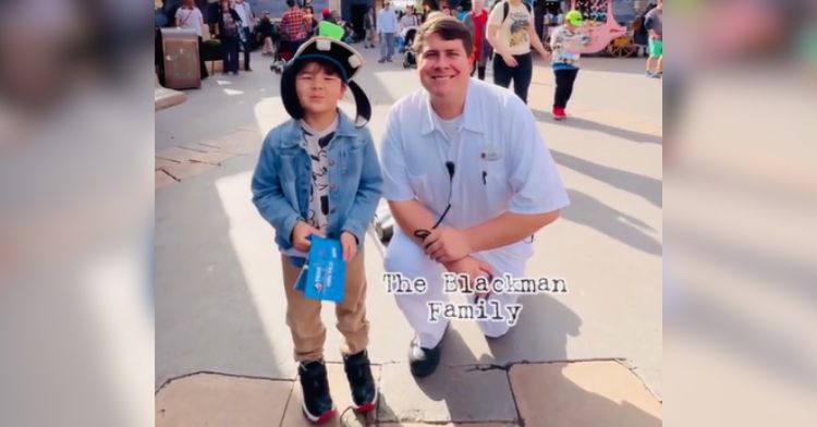 A little boy poses with a Disney employee after getting his signature.