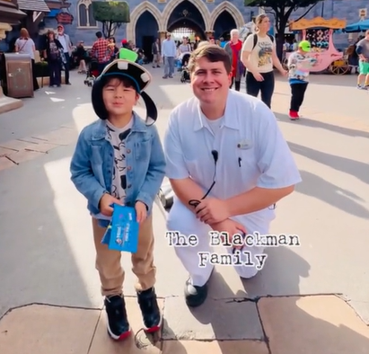 A little boy poses with a Disney employee after getting his signature. 