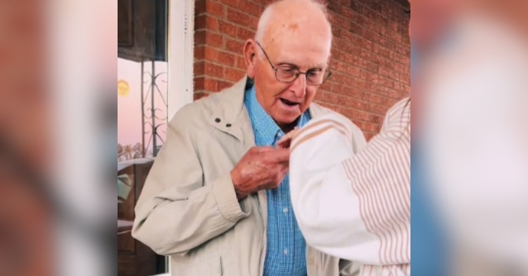 An elderly man's eyes are wide and his mouth is agape as he holds onto and looks at the hand of his great granddaughter, Haley Anderson.