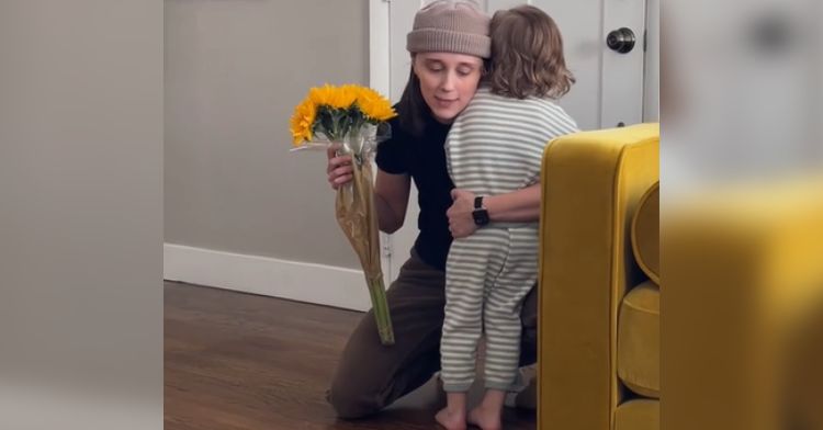 A mom buys yellow flowers for her toddler son.