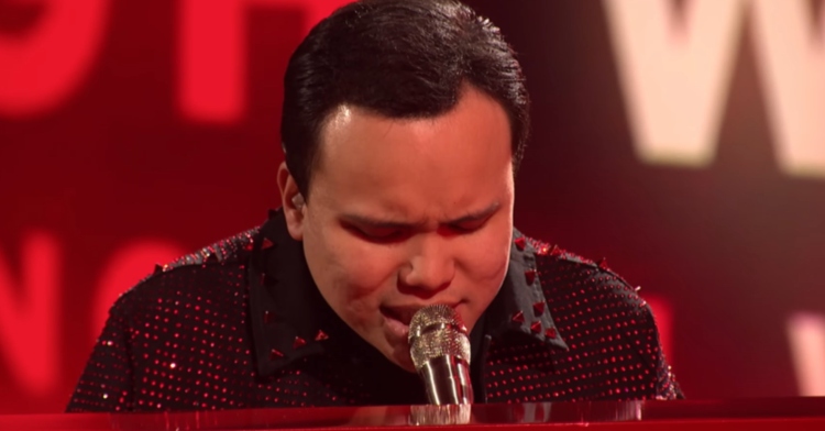 View of Kodi Lee singing into a microphone while playing the piano on "America's Got Talent: Fantasy League."