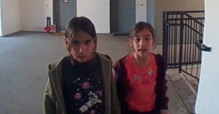 Two little girls look serious as they talk to their neighbor, Brina, through her Ring camera about her fire alarm going off.