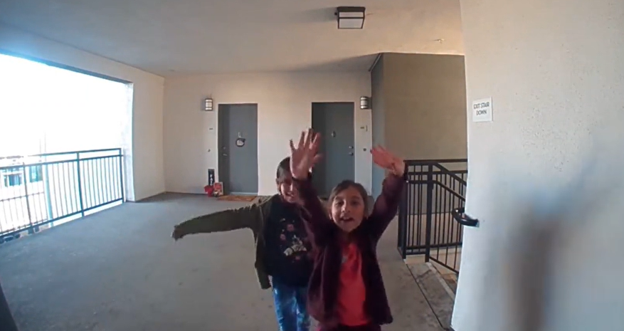 Two little girls smile and wave at the Ring camera of a neighbor named Brina.