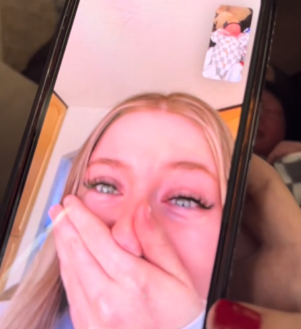 View of Gwendalyn McHaddad FaceTiming a friend for the best newborn baby surprise. Her friend's face looks red and her eyes are watery. She has one hand covering most of her face.