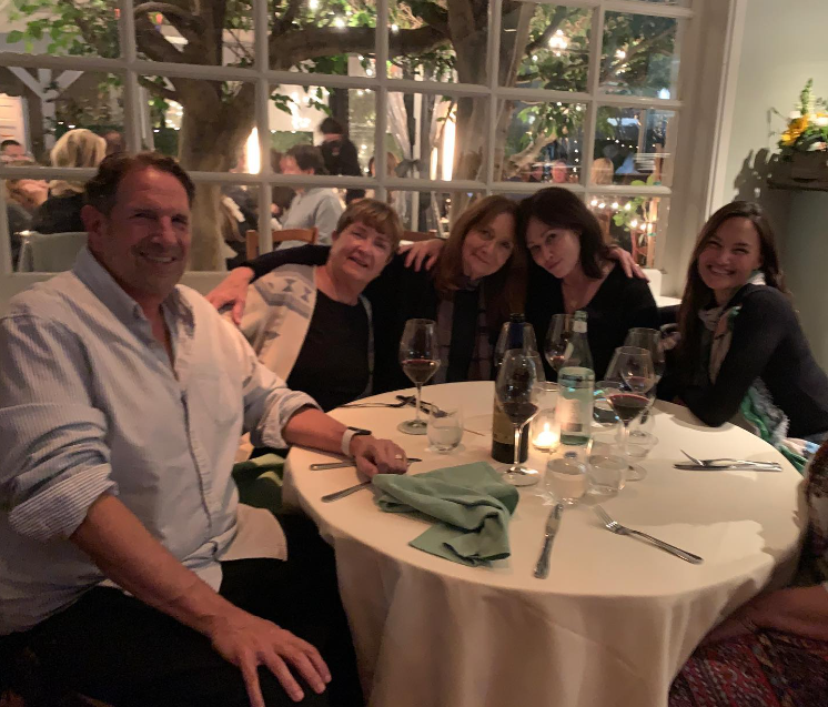 Shannen Doherty smiles and poses at a restaurant table with four family members, including her mom.