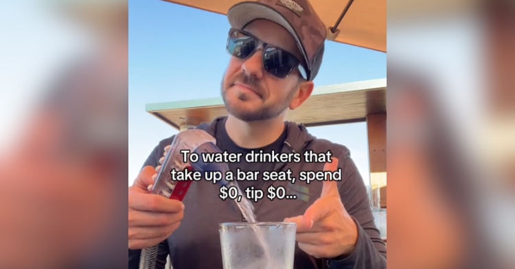 Bartender wearing sunglasses points to a glass as he pours water into it. Text on the image reads: To water drinkers that take up a bar seat, spend $0, tip $0…