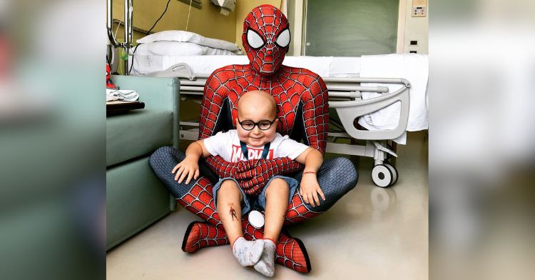 Spiderman visits a boy with leukemia in the hospital.