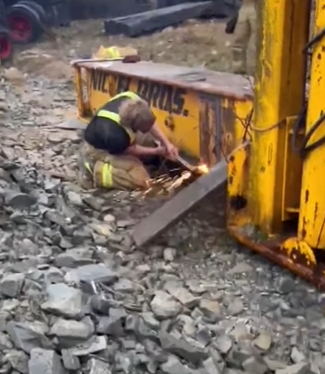 A firefighter cutting into a piece of equipment.