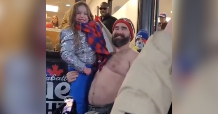 Jason Kelce smiles as he holds up a little girl in his arms, who he just helped see Taylor Swift at the Chiefs-Bills game.