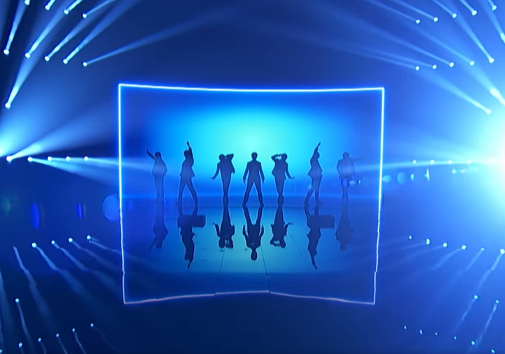 Travis Japan on the "AGT" stage. The lighting is blue and their silhouettes can be seen posing in various positions. 