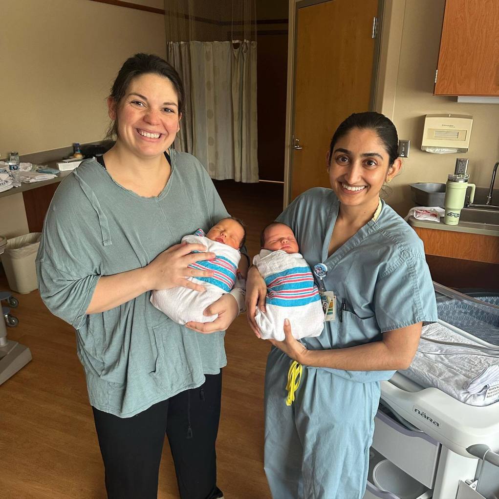 A mom and her doctor hold a pair of newborn twins. 