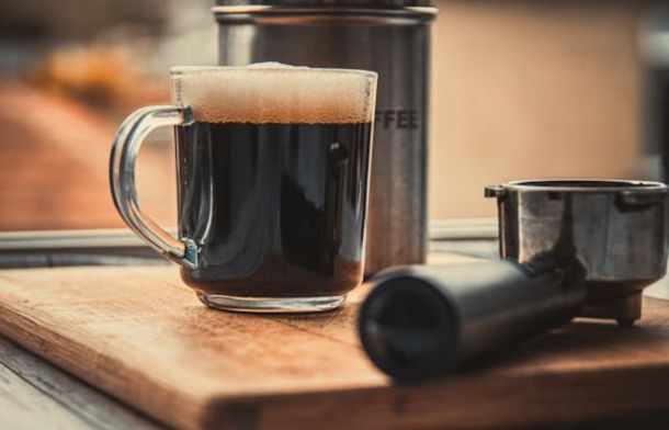 Image showing a full coffee mug, hand grinder, and French press.