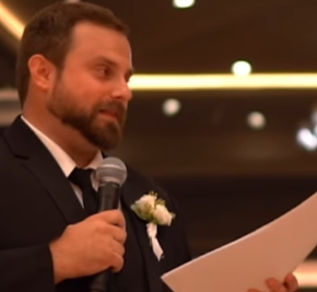 Dylan holds a mic and paper as he gives his best man speech.