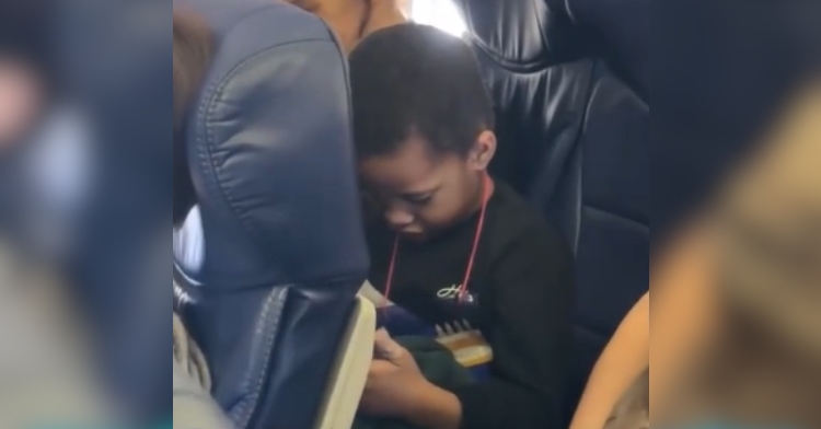 A little boy looks down as he sits alone on an airplane on his birthday.