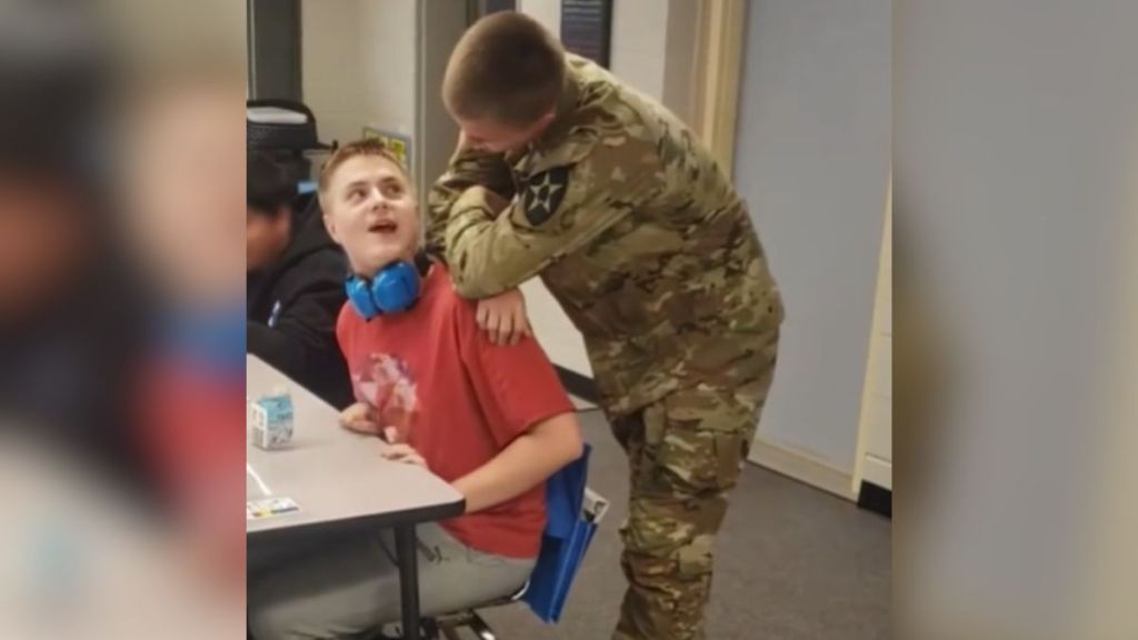 A man in a military uniform sneaks up behind his surprised brother.