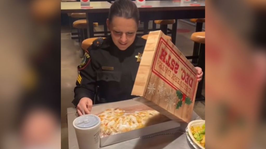 A police woman is surprised when she opens a pastry box in a restaurant.